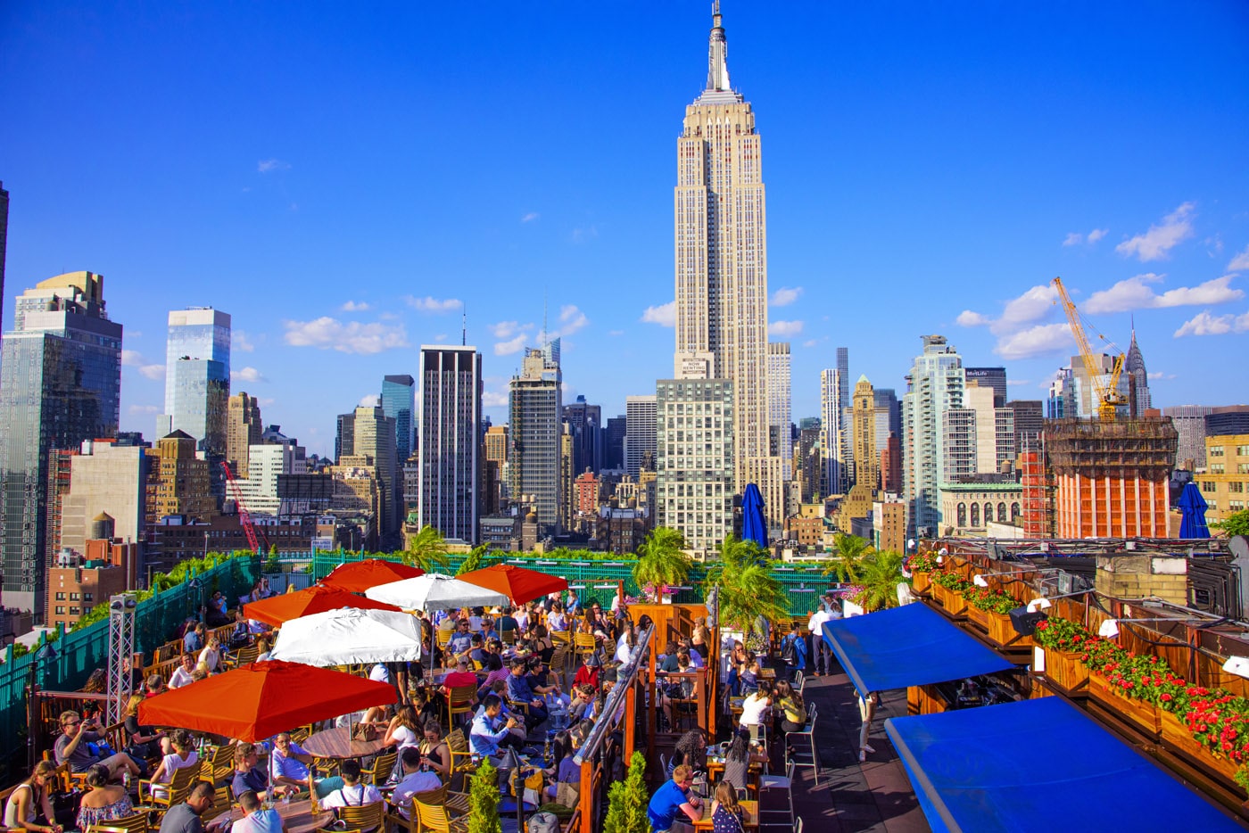 Het terras van 230 Fifth Rooftop met parasols en uitzicht op het Empire State Building.