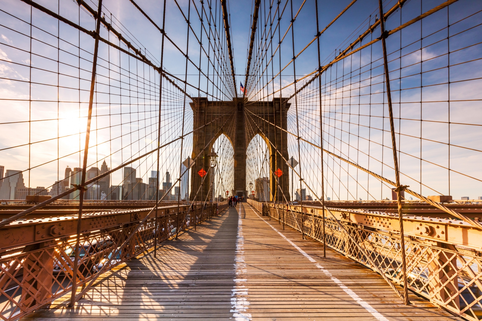 Het houten wandelpad en de kabels van de Brooklyn Bridge in warm zonlicht.