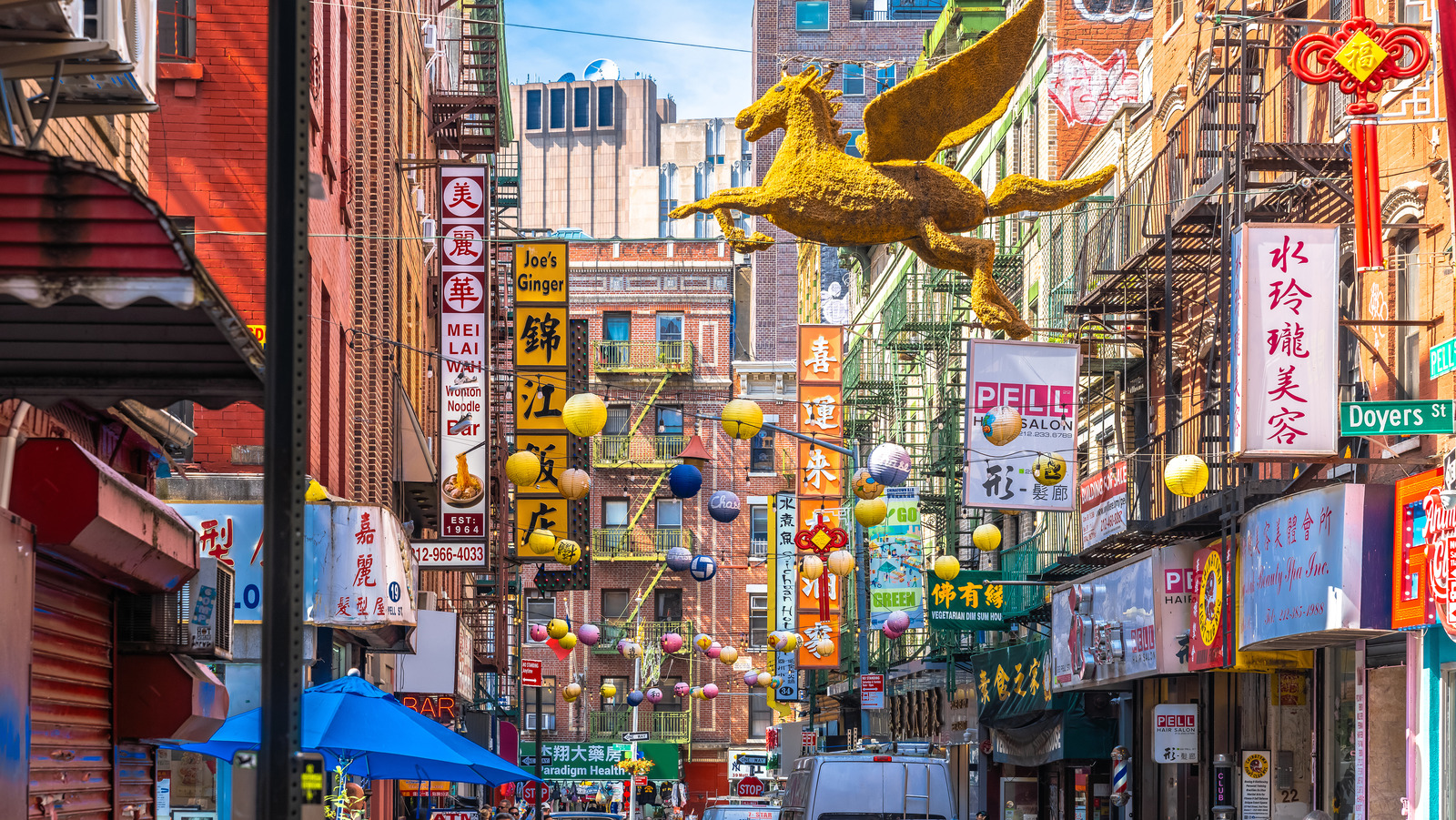 Een kleurrijke straat in Chinatown met Chinese uithangborden, lampions en een gouden gevleugeld paard.