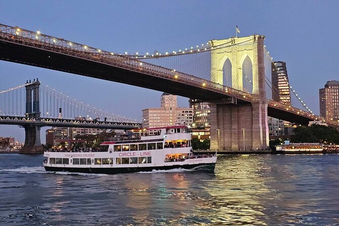 Een Circle Line-boot onder de verlichte Brooklyn Bridge tijdens de avondschemering.