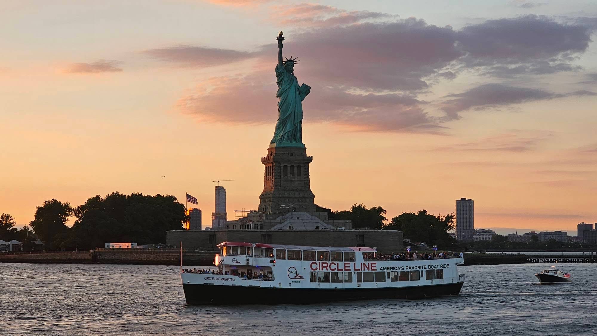 Een Circle Line-boot voor het Vrijheidsbeeld bij zonsondergang.