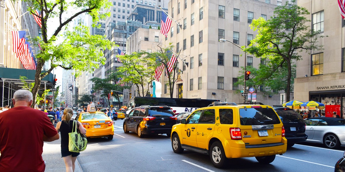Gele taxi’s, winkels en Amerikaanse vlaggen op Fifth Avenue.
