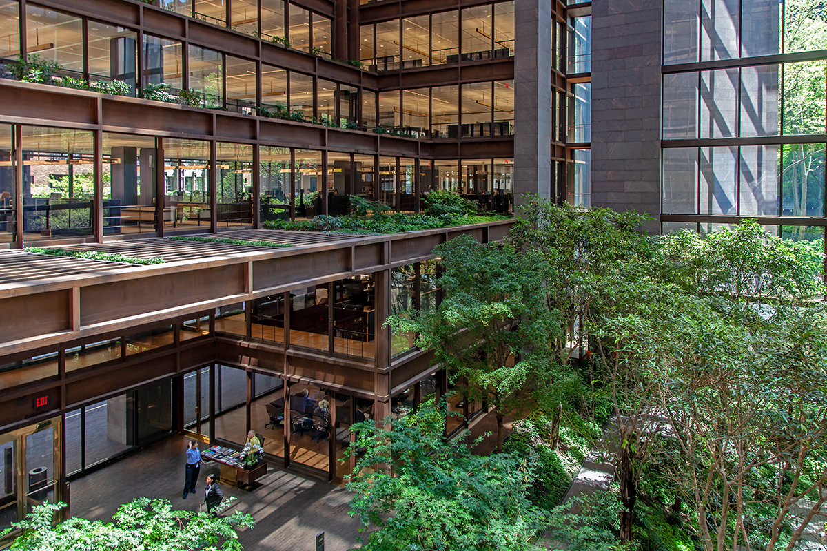 De groene binnentuin van de Ford Foundation onder hoge ramen en galerijen.