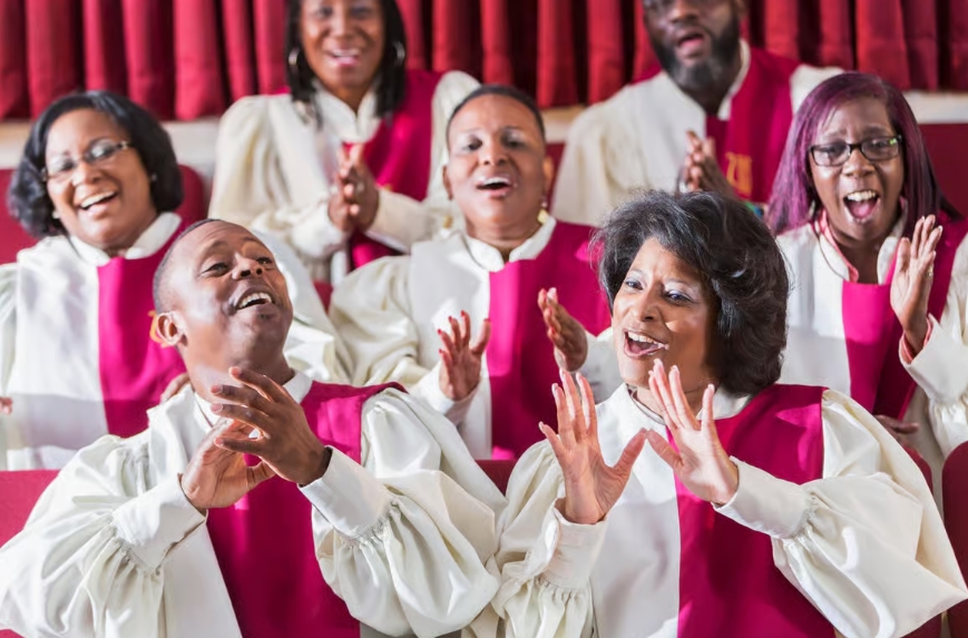Een gospelkoor dat zingt en klapt in witte gewaden met roze accenten.