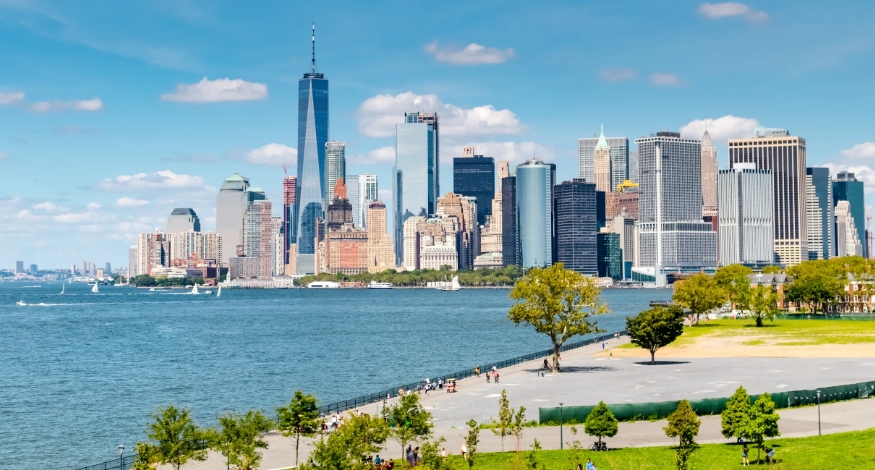 De groene waterkant van Governors Island met uitzicht op de skyline van Lower Manhattan.