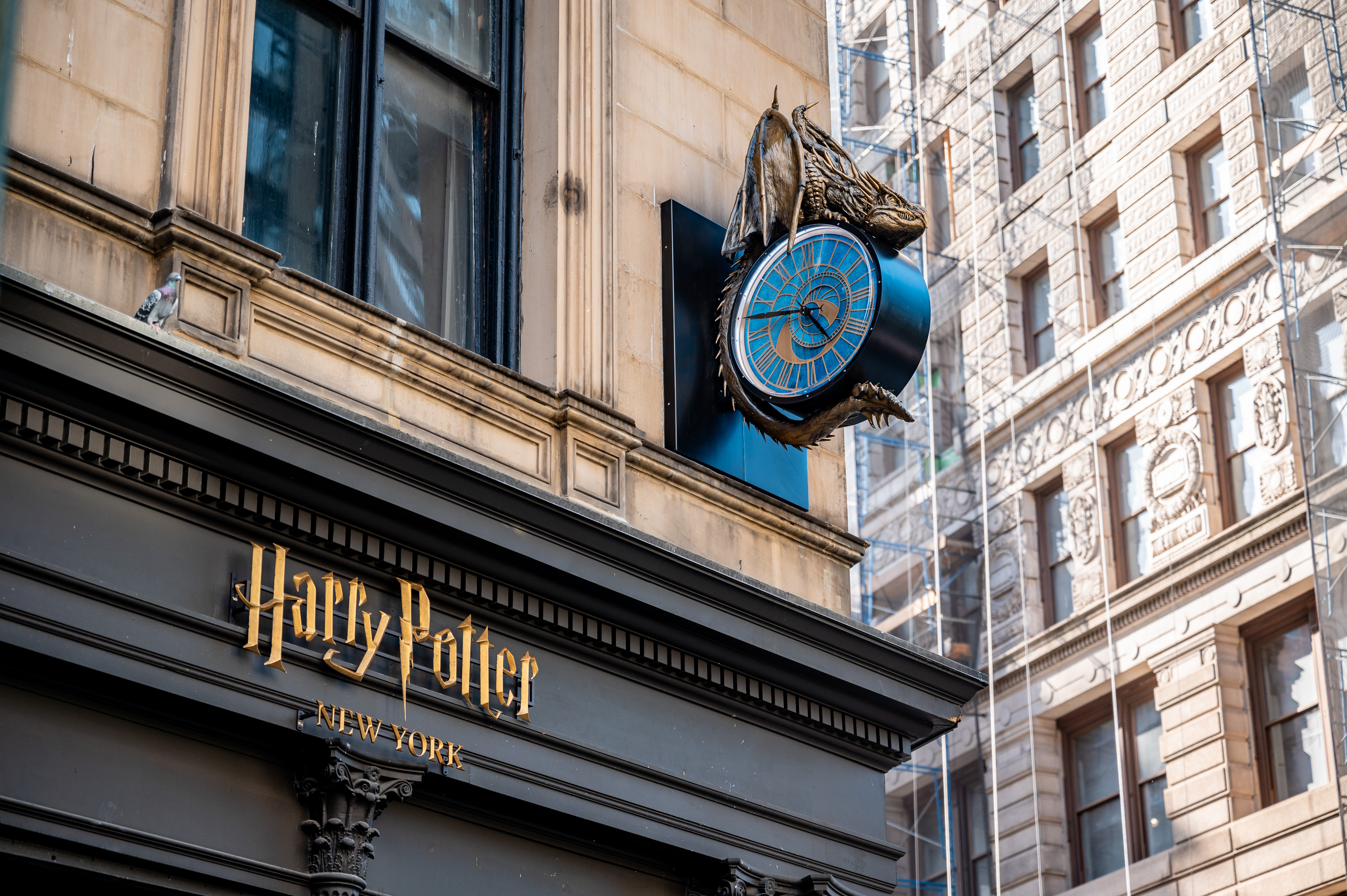 De gevel van Harry Potter New York met gouden winkelletters en een blauwe klok met draak.