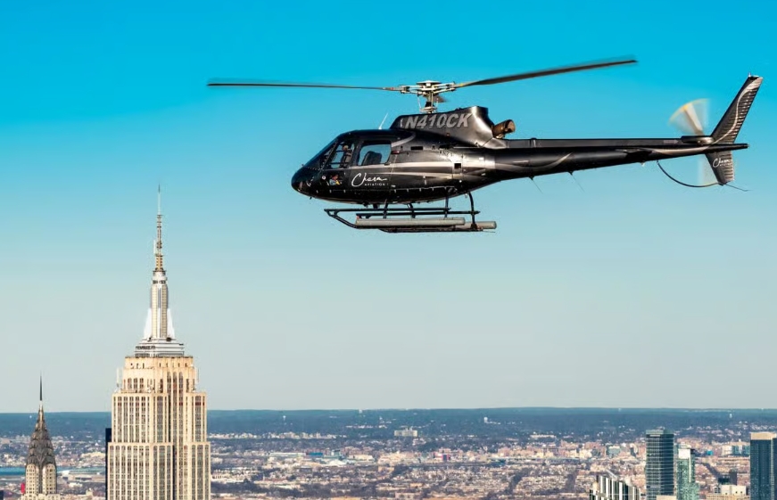 Een zwarte helikopter boven Manhattan met het Empire State Building op de achtergrond.