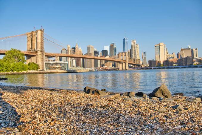 Kiezels op Pebble Beach met uitzicht op de Brooklyn Bridge en de skyline van Manhattan.