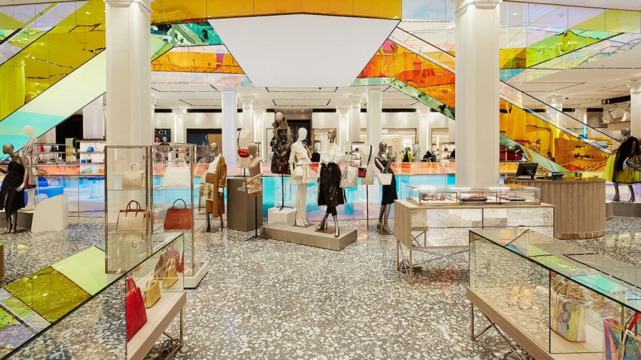 Het interieur van Saks Fifth Avenue met kleurrijke glazen roltrappen en modepresentaties.